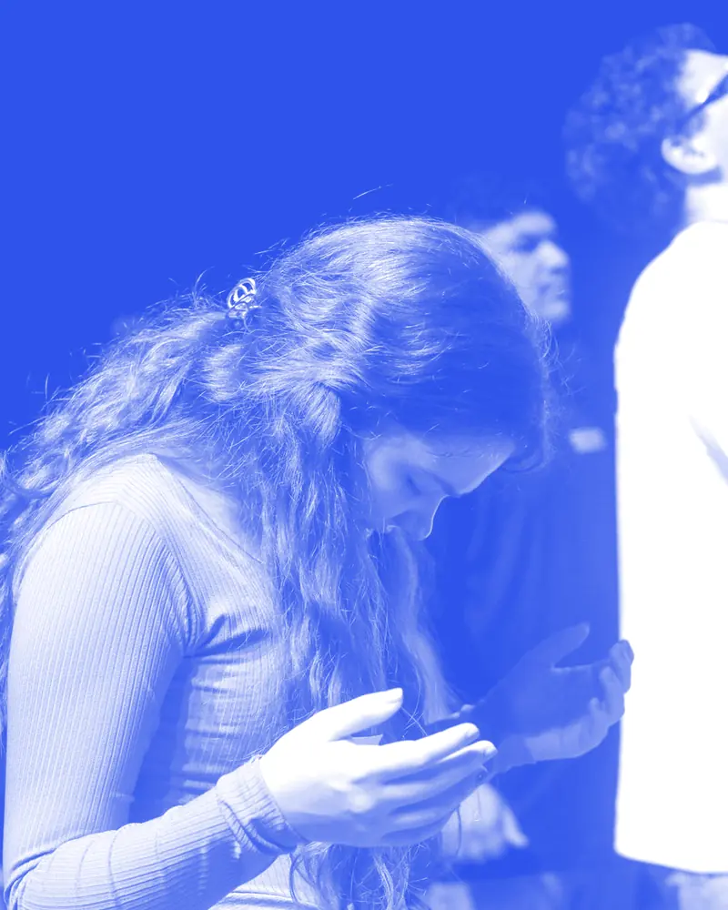 Jovem em oração no meio da igreja, na Conferência ONE 2025